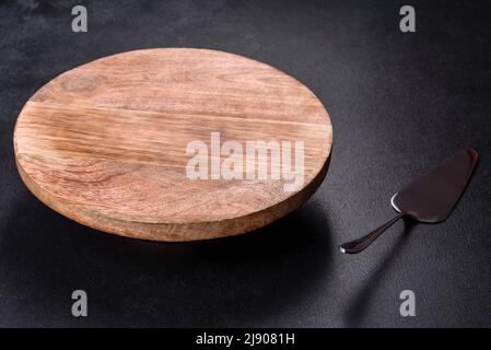 A metal cake blade with an empty brown cake stand on a dark concrete background. Preparing a festive table Stock Photo
