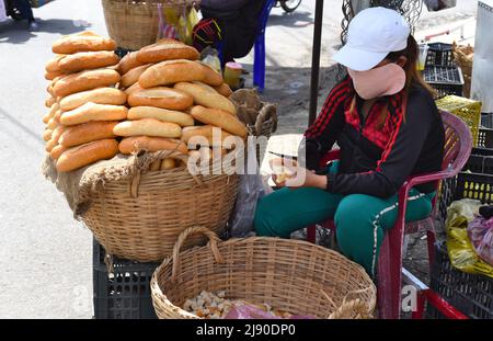 Nha Trang, Vietnam - 17 May 2022: Vietnamese woman sells french baguette on the market of Nha Trang Stock Photo