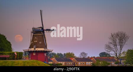 Sunset and moonrise with a full moon near Flour Mill "De Hoop" in the Dutch town of Dokkum, in the province of Friesland in the northern part of the N Stock Photo