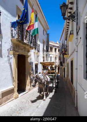 RONDA, ANDALUCIA, SPAIN - MAY 8 : Tourists enjoying a ride in a horse drawn carriage in Ronda Spain on May 8, 2014. Three unidentified people. Stock Photo