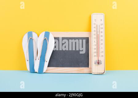 Empty chalkboard with a thermometer and flip flops, holiday background, summer vacation, hot weather, environmental issue Stock Photo