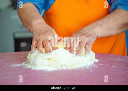 grandmother kneads dough for Easter cakes on the table Stock Photo