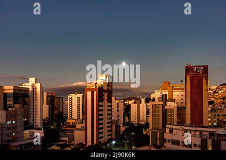 City of Belo Horizonte in the southeastern region of Brazil seen at dusk with the full moon over the buildings, Stock Photo