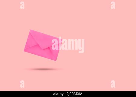 A pink envelope floating on a pink background with copy space Stock Photo