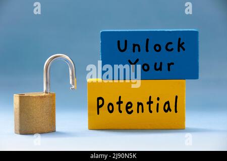Unlock your potential text on wooden blocks with pad lock on light blue background. Motivational concept Stock Photo