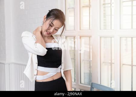 Office syndrome concept. Businesswoman massaging neck, suffering from pain after sedentary working in incorrect posture. Employee massaging stiff neck Stock Photo