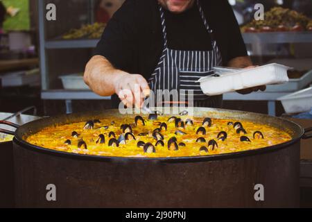 cook prepares mussels seafood in a vat on a fire steaming in oil