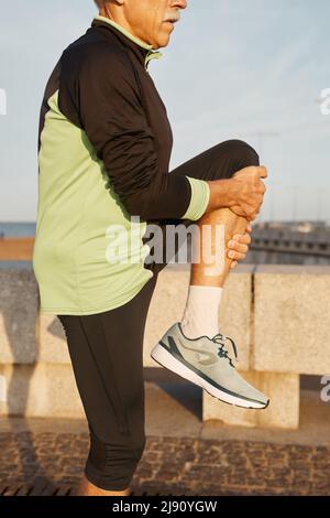 Medium long side view shot of unrecognizable man doing morning exercise outdoors Stock Photo