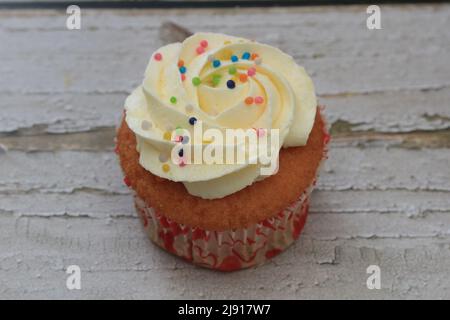 Sweet cake with tutti frutti sprinkles on top on the wooden table white background. Stock Photo