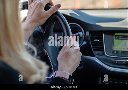 woman driving car, presses finger on touch screen, using car navigation system Stock Photo