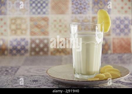 Alternative, non-dairy milk. Lactose free, environment friendly potato milk and potato on the plate on the table. Tile classic background. Copy space Stock Photo