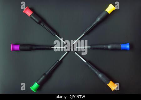 Set of screwdrivers with multi-colored handles on black background. Folded in form of star. Top view. Selective focus. Close-up. Copy space. Stock Photo