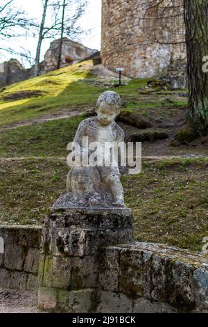 Travertine sculpture - a figure of a child with owl at the step’s edge in the Cesis Castle Park's hill, Latvia. Stock Photo