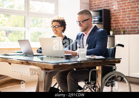 Two Young Businesspeople Working On Laptop At Workplace Stock Photo