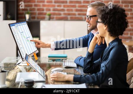 Mature Businesspeople Analyzing Gantt Chart And Calendar On Computer In Office Stock Photo