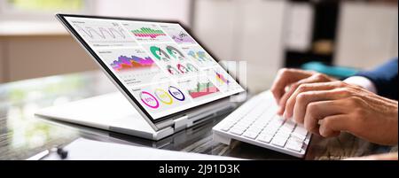 Close-up Businessman's Hand Pointing Bar Graph On Laptop Screen Over White Desk At Workplace Stock Photo