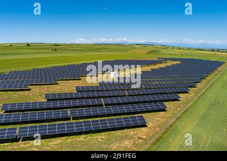 Aerial view photovoltaic panels park on green field in north Greece. Blue sky reflecting in solar panels rows. Futuristic alternative power station. S Stock Photo