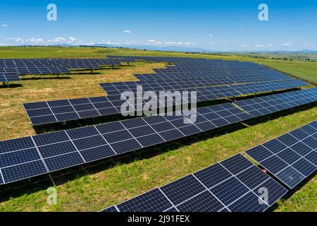 Aerial view photovoltaic panels park on green field in north Greece. Blue sky reflecting in solar panels rows. Futuristic alternative power station. S Stock Photo