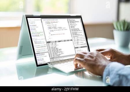 Programmer Or Coder At Office Desk Using Laptop Stock Photo