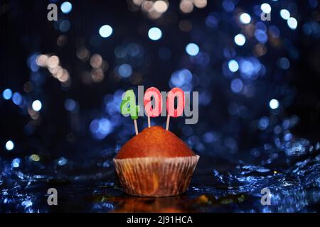 Tasty homemade vanilla anniversary cupcake with number 400 four hundred on aluminium foil and blurred bright background in minimalistic style. Digital gift card birthday concept. High quality image Stock Photo