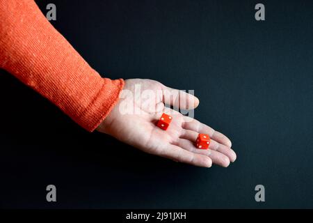 Red dices in male hand pointing down. Copy space. Close-up. Selective focus. Stock Photo
