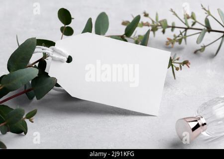 Rectangle white gift tag mockup with eucalyptus leaves on grey background, label tag mockup, Wedding favor tag for souvenir, sign for greeting message Stock Photo