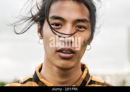 Asian young man looking at camera outdoor - Focus on face Stock Photo