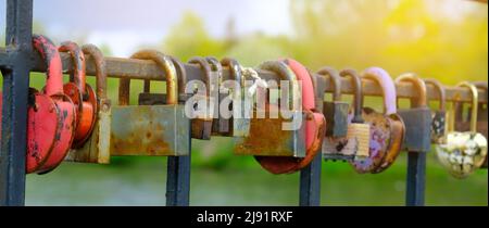 Locks of love on the railing in the city park. Many locks of love hang on a metal fence in a city park Stock Photo