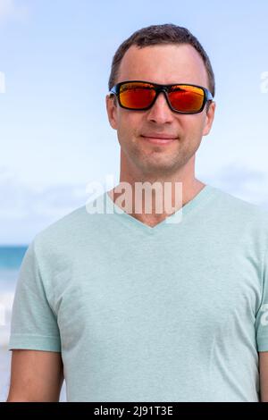 Close up portrait of young adult Caucasian man in shiny red sunglasses Stock Photo