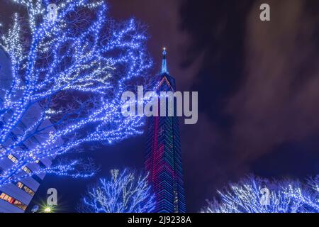 kyushu, fukuoka - december 06 2021: Night view of illuminated trees with blue lights garlands at foot of the tallest seaside tower in Japan, the Fukuo Stock Photo