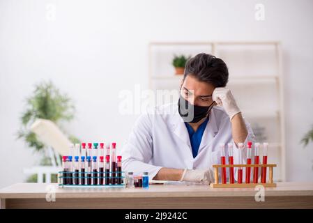 Young biochemist testing blood samples in pandemic concept Stock Photo
