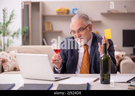 Old businessman employee drinking champagne at home Stock Photo