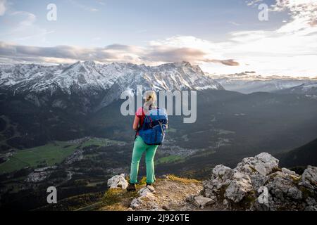 Young hiker at the Kramerspitz, Wetterstein Mountains and Zugspitze in the background, Bavaria, Germany Stock Photo