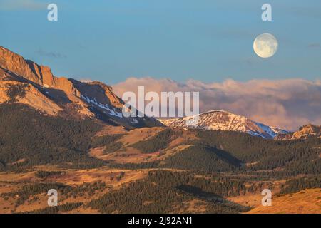full moon setting over the rocky mountain front near augusta, montana Stock Photo
