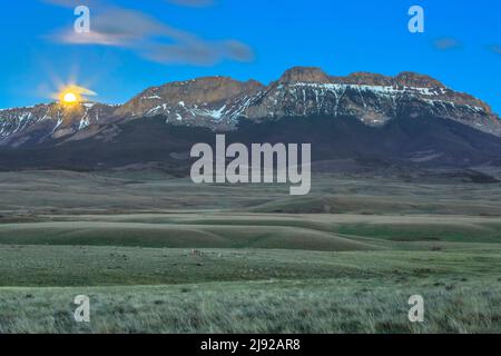 full moon setting behind sawtooth ridge on the rocky mountain front near augusta, montana Stock Photo