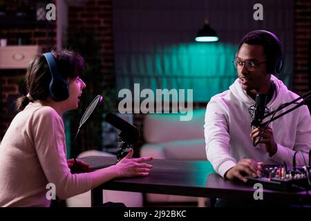 Male influencer hosting podcast livestream with woman, recording online conversation for social media content. Lifestyle blogger meeting with female guest to broadcast channel interview. Stock Photo