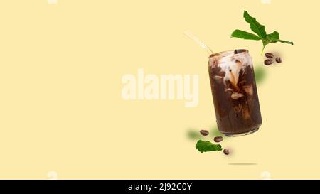Floating can-shaped glass cup with coffee, coffee beans, coffee leaves flying on a yellow background Coffee drink with plant-based milk. Stock Photo