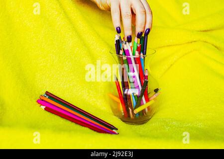 Colored pencils on the yellow background. Top view. Stock Photo