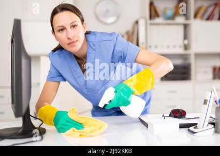 Portrait of a young woman cleaning an office desk Stock Photo