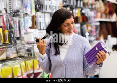 Smiling latina choosing hair rollers in store Stock Photo
