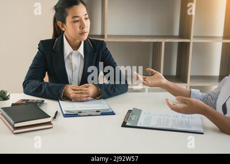 Asian young adult sitting at desk across from manager being interviewed job interview in business room. Stock Photo