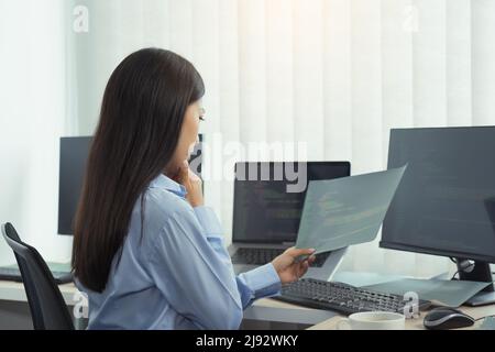 Asian woman was stressed in the early morning while contemplating the programs and codes on the computer screen. Stock Photo