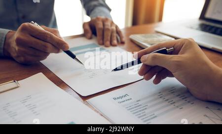 Managers are using tablets to analyze sales cost reports and explain summary reports to employees calculate and record summary information data in the Stock Photo