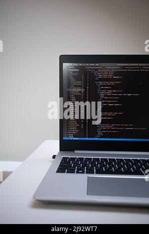 Opened laptop with code on the screen on the table Stock Photo