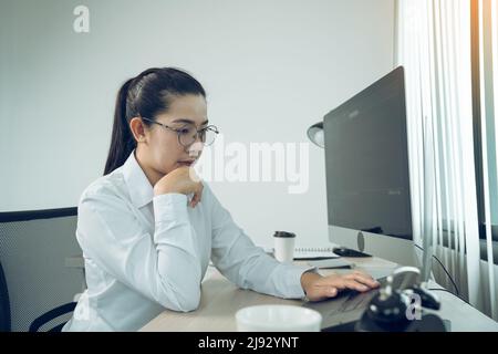 Asian female software developer is worried about analyzing code-based systems at his office. Stock Photo
