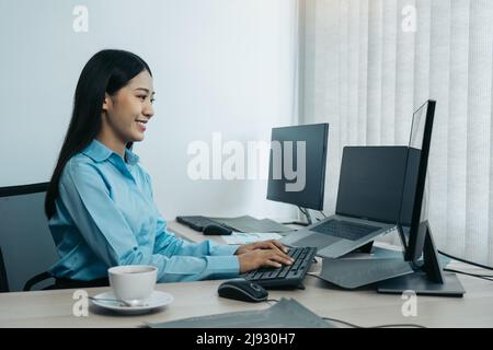 Business woman working on desktop computer monitor professional and sitting at her office desk and working on new software program. Stock Photo