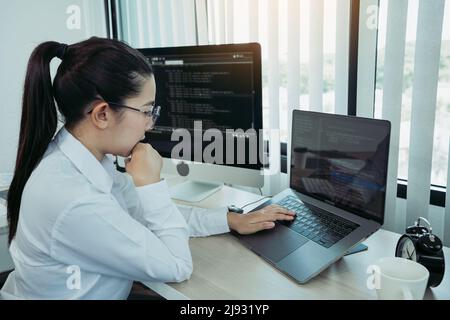 Asian female software developer is worried about analyzing code-based systems at his office. Stock Photo