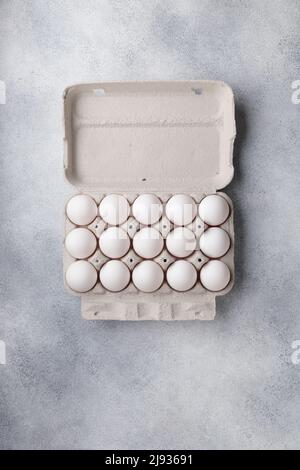 White eggs in a large paper container box top view on a neutral background Stock Photo