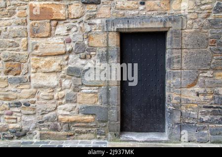 Beautiful old medieval European stone wall texture background, with view of an old metal door Stock Photo