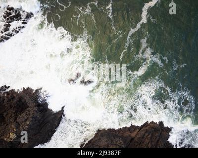 Shot from the air. Storm in the ocean. White foamy waves crash against the rocks on the shore. Magical seascape. Beautiful nature. Tourist direction. Stock Photo